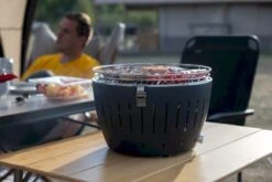 LotusGrill XL Hybrid Houtskoolbarbecue - Rood 20 LotusGrill XL Hybrid Houtskoolbarbecue - Rood -Bo-Camp Verkoop lotusgrill in gebruik met toppy shirtje 2